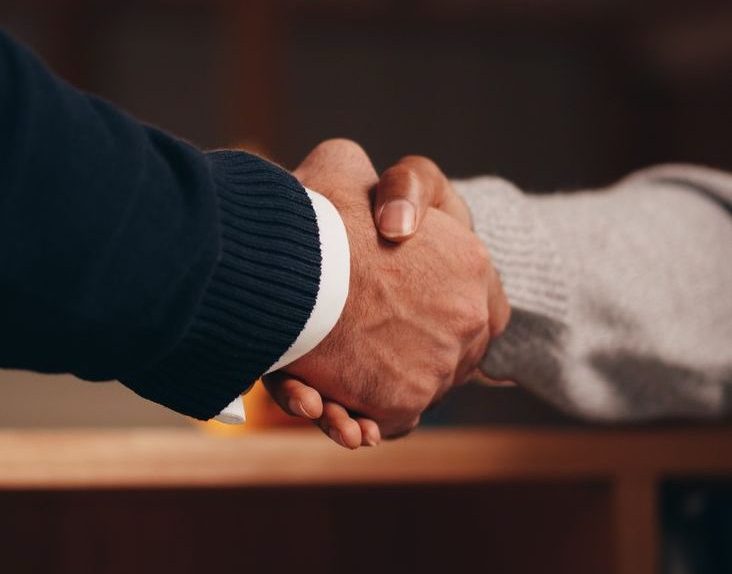 a person in black long sleeve shirt shaking the hands of a person in gray long sleeve shirt